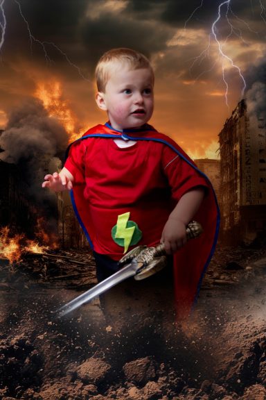 A little boy with pale skin and blonde hair dressed as a superhero, holding a sword, with a background of a destroyed city and lightening.